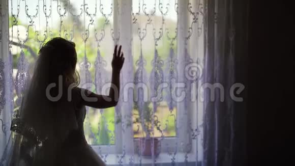 女人揭开窗帘的剪影望着窗外视频的预览图