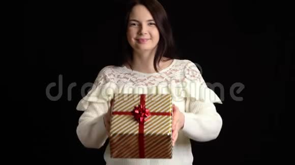 年轻女子在黑色背景上赠送礼品盒带白色丝带的礼品盒祝新年快乐圣诞快乐视频的预览图