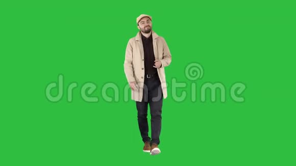 穿着风衣的年轻人在绿色屏幕上打招呼Chroma键视频的预览图
