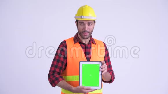 一位满脸胡须的波斯建筑工人一边说一边展示数字平板电脑视频的预览图