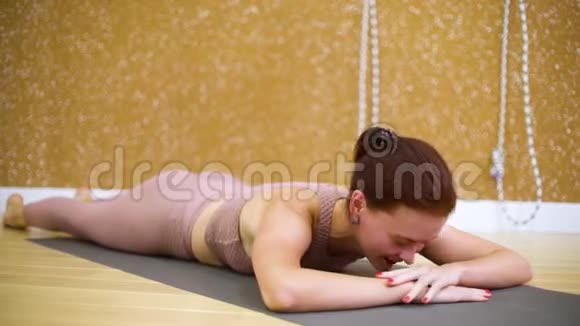 年轻女子躺在垫子上慢动作在瑜伽馆做瑜伽练习视频的预览图