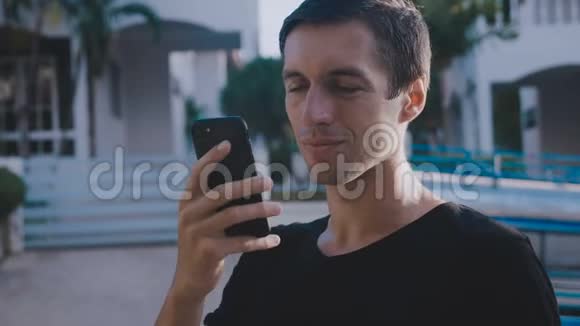 微笑的男人用智能手机说话英俊快乐的年轻男性在街上用手机说话的肖像视频的预览图