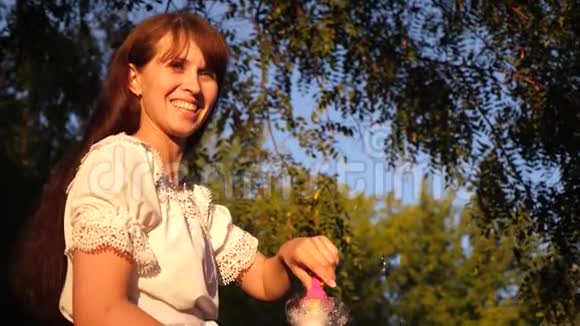 女人在公园散步时吹大肥皂泡笑大自然中的夏日散步和游戏视频的预览图