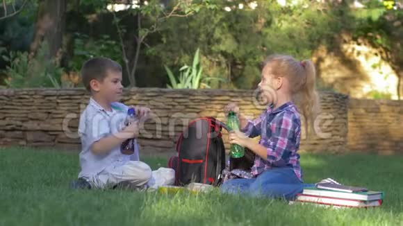 口渴的孩子把瓶盖拧在瓶子上午饭时在校园里快速地喝果汁视频的预览图
