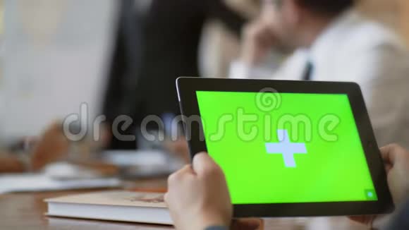 在办公室的一次会议上一位特写员工拿着一块绿色屏幕的平板电脑视频的预览图