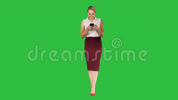 成功的女性雇主在绿色屏幕上行走时在手机上键入短信Chroma键视频的预览图