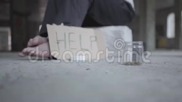 脚的赤脚可怜的女孩在混凝土地板上一个模糊的标志上面写着帮助和罐子硬币躺在前景视频的预览图
