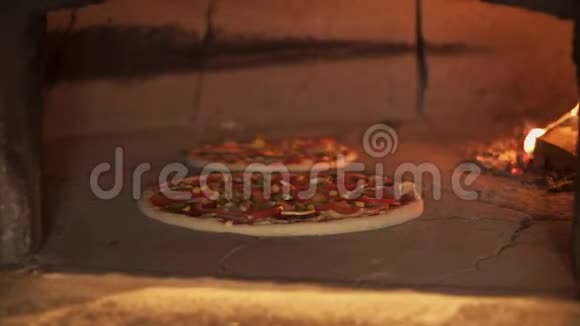 把两个蔬菜披萨放进砖烤箱里视频的预览图