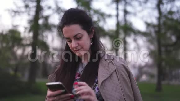 年轻女子用手机拍摄背景中的樱花生活方式视频的预览图