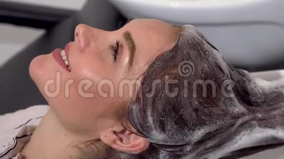 女人一边享受头部按摩一边给理发师洗头视频的预览图