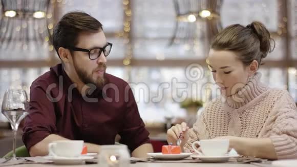 在餐馆里一个年轻的男人和一个女人用勺子互相喂蛋糕视频的预览图