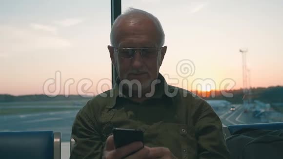 一位白发苍苍胡须苍白的老人正在机场等候登机他用智能手机打发时间视频的预览图