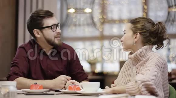 一对漂亮的夫妇坐在一桌一桌的餐馆里当服务员拿着一盒装满鲜花的盒子男人把它送给他的时候视频的预览图