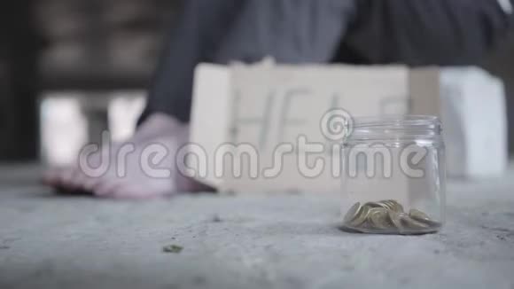 脚的赤脚可怜的女孩在混凝土地板上一个模糊的标志上面写着帮助和罐子硬币躺在前景视频的预览图