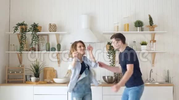 快乐的年轻夫妇穿着牛仔裤跳舞在厨房跳舞视频的预览图
