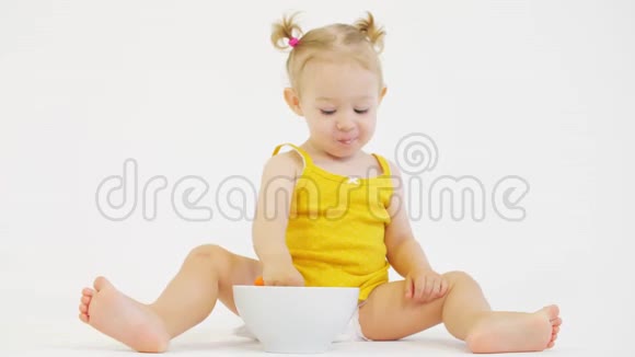 快乐的女婴在白色背景下吃麦片视频的预览图