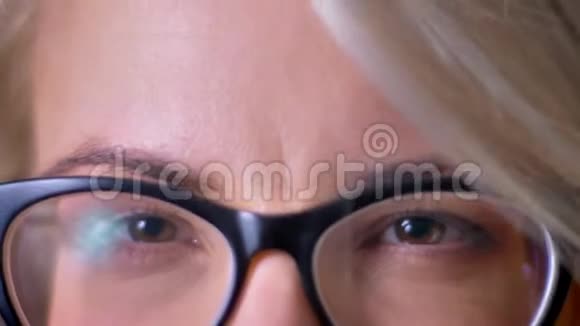 特写肖像的女性棕色眼睛戴着黑色眼镜直接观看进入相机视频的预览图