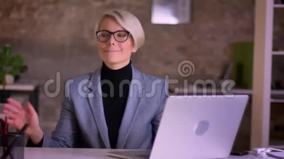 戴眼镜的中年短发女商人的肖像在办公室的座位上积极地跳舞视频的预览图
