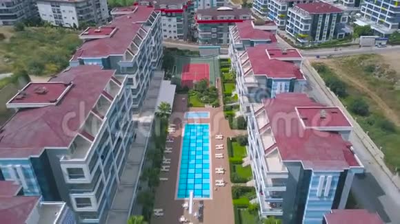 酒店自上而下的鸟瞰游泳池蓝色的水周围有其他建筑物和绿色草坪艺术视频的预览图