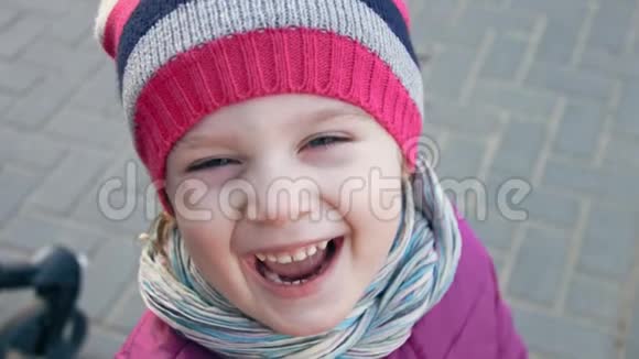 一个漂亮的白种人小女孩戴着条纹帽子漂亮的蓝眼睛看着镜头视频的预览图
