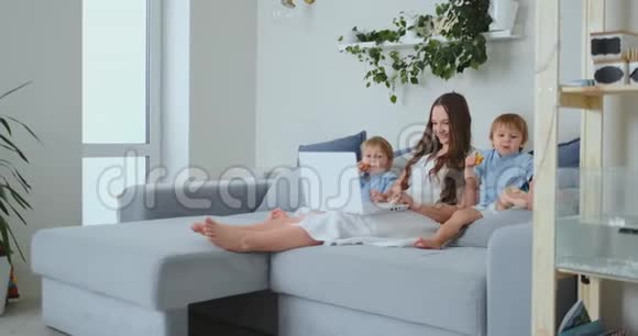 漂亮的年轻妈妈和两个小男孩正在看手提电脑屏幕的家庭照片做网上购物视频的预览图