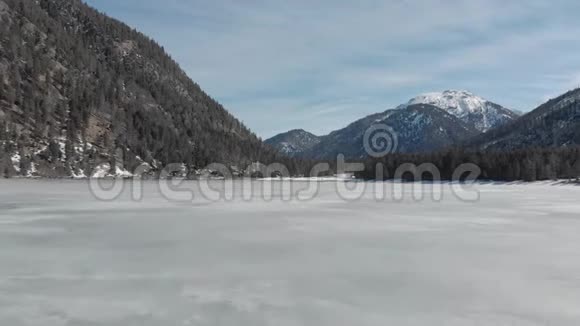 在冬季山脉之间的冰湖中进行旅游旅行在旅行时用松树对抗蓝天视频的预览图