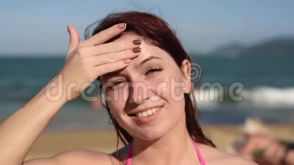 一位美丽的年轻女子的肖像微笑着穿着比基尼脸上涂着防晒霜海底视频的预览图