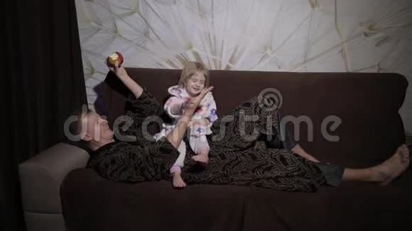 小女儿和父亲一起看有趣的电影吃苹果视频的预览图