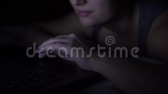 迷人的快乐女人在晚上躺在床上在笔记本电脑键盘上打字特写镜头4K视频的预览图