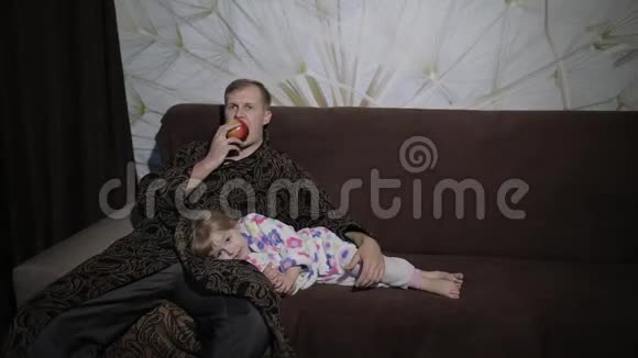 小女儿和父亲一起看有趣的电影吃苹果视频的预览图