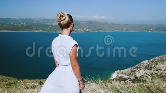 穿着白色夏装的女人从地中海顶级风景中欣赏着装在风中飞扬令人惊叹视频的预览图
