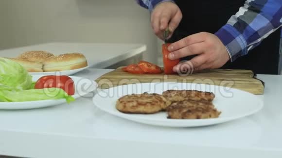 丰满的家伙在他的厨房里做家庭汉堡包人在砧板上切西红柿不健康的生活方式油炸和视频的预览图