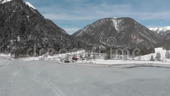 冬季旅行从空中俯瞰游客在山上结冰的湖面上的休息综合体树木映衬着晴朗的天空视频的预览图