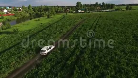 侧面鸟瞰大型银色SUV在绿色的田野上行驶视频的预览图