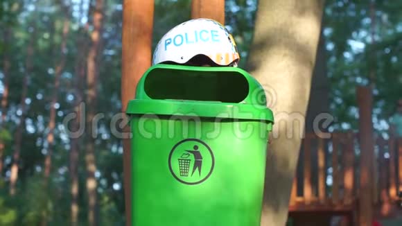 戴着铭文的头盔警察躺在一个绿色的垃圾桶上视频的预览图