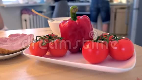 厨房桌子上的辣椒西红柿和火腿家人正在家里做饭视频的预览图