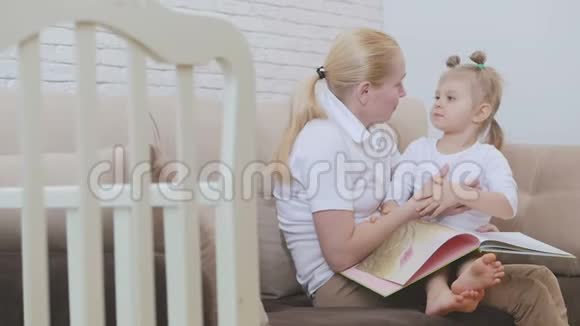 女人亲吻坐在家里沙发上的小女孩视频的预览图
