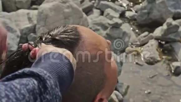 人头发是从辫子女人编织男人的头发男孩做维京人的发型在一条山河附近织毛视频的预览图
