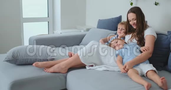 孩子们抱着妈妈坐在沙发上看电视视频的预览图