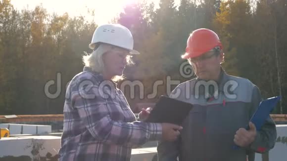 建筑工人和工头戴着头盔和护目镜站在建筑上防晒视频的预览图