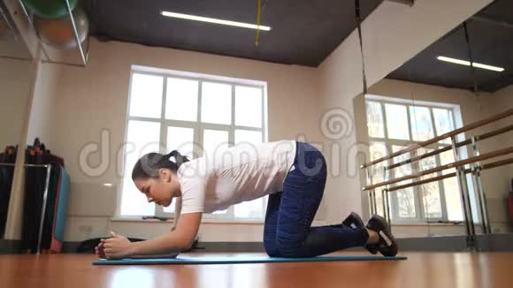 女孩做运动木板站在健身室中间的垫子上4K慢慢视频的预览图