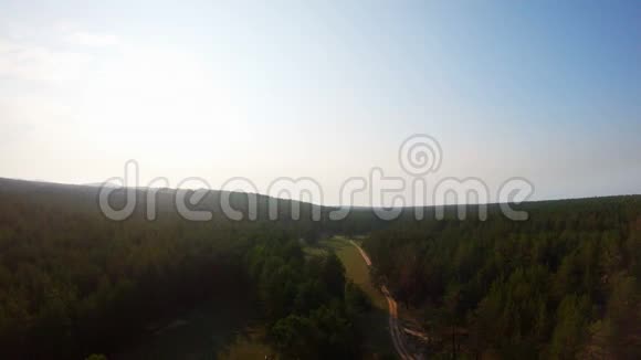 日落时分无人机飞过森林空地和乡村道路视频的预览图
