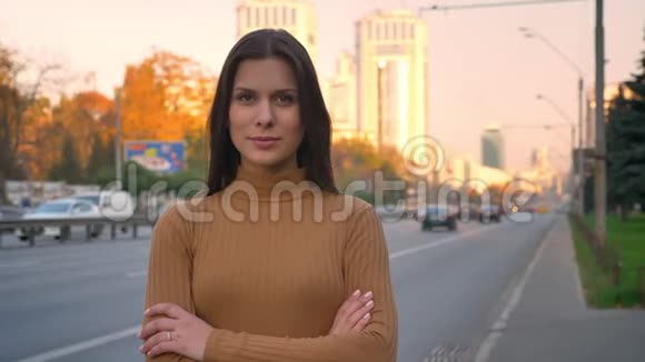 一幅严肃的白种人深色头发的肖像她用双臂谨慎地注视着镜头交叉在道路背景上视频的预览图