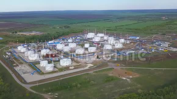 从空中可以看到大型的白色圆形水库在天然气和炼油厂的绿色草坪中有蓝色的管道剪辑视频的预览图
