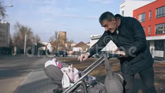 成熟的男人推着婴儿车和孙女玩在美丽的春天散步祖父和祖父视频的预览图