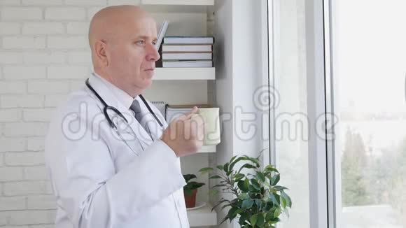 带着放松的医生在医疗室喝咖啡或茶慢动作视频的预览图