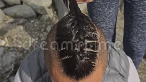 人头发是从辫子女人编织男人的头发男孩做维京人的发型在一条山河附近织毛视频的预览图