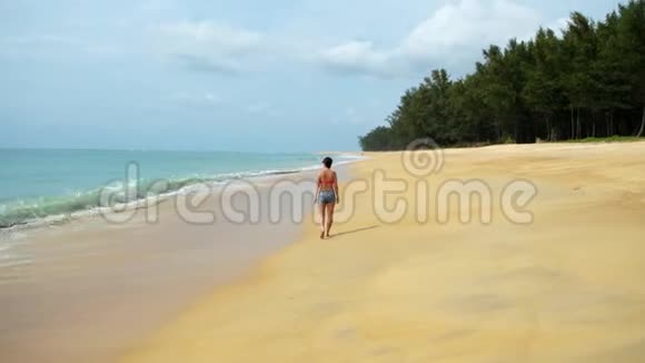 美丽的女人走在海岸线上女孩的腿水沫热带海洋平静的海上生活时尚视频的预览图
