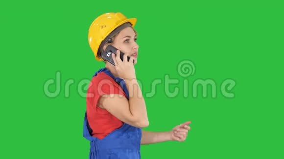 漂亮的年轻建筑工女戴着黄色的安全帽在绿色屏幕上打电话Chroma键视频的预览图
