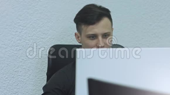 在他工作的地方用电脑把一个有魅力的年轻人关起来办公室工作人员视频的预览图